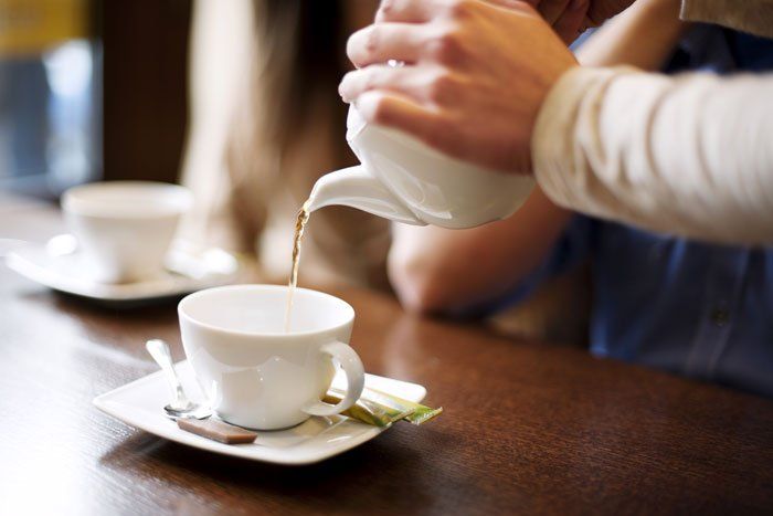 waiter pours tea to customers after their meal